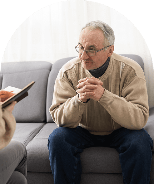 Elderly man sitting on a couch talking.